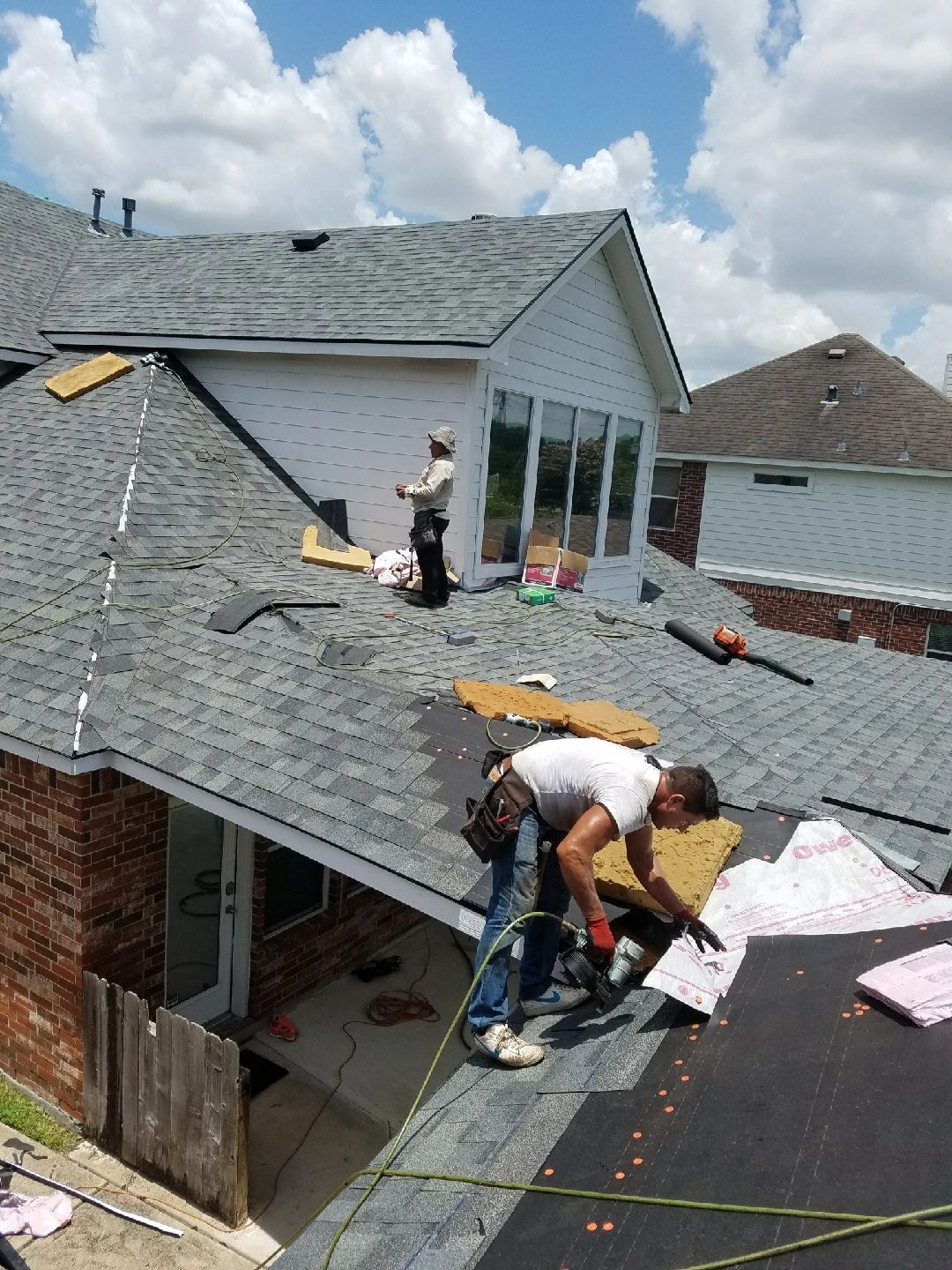 Workers installing shingles on residential roof
