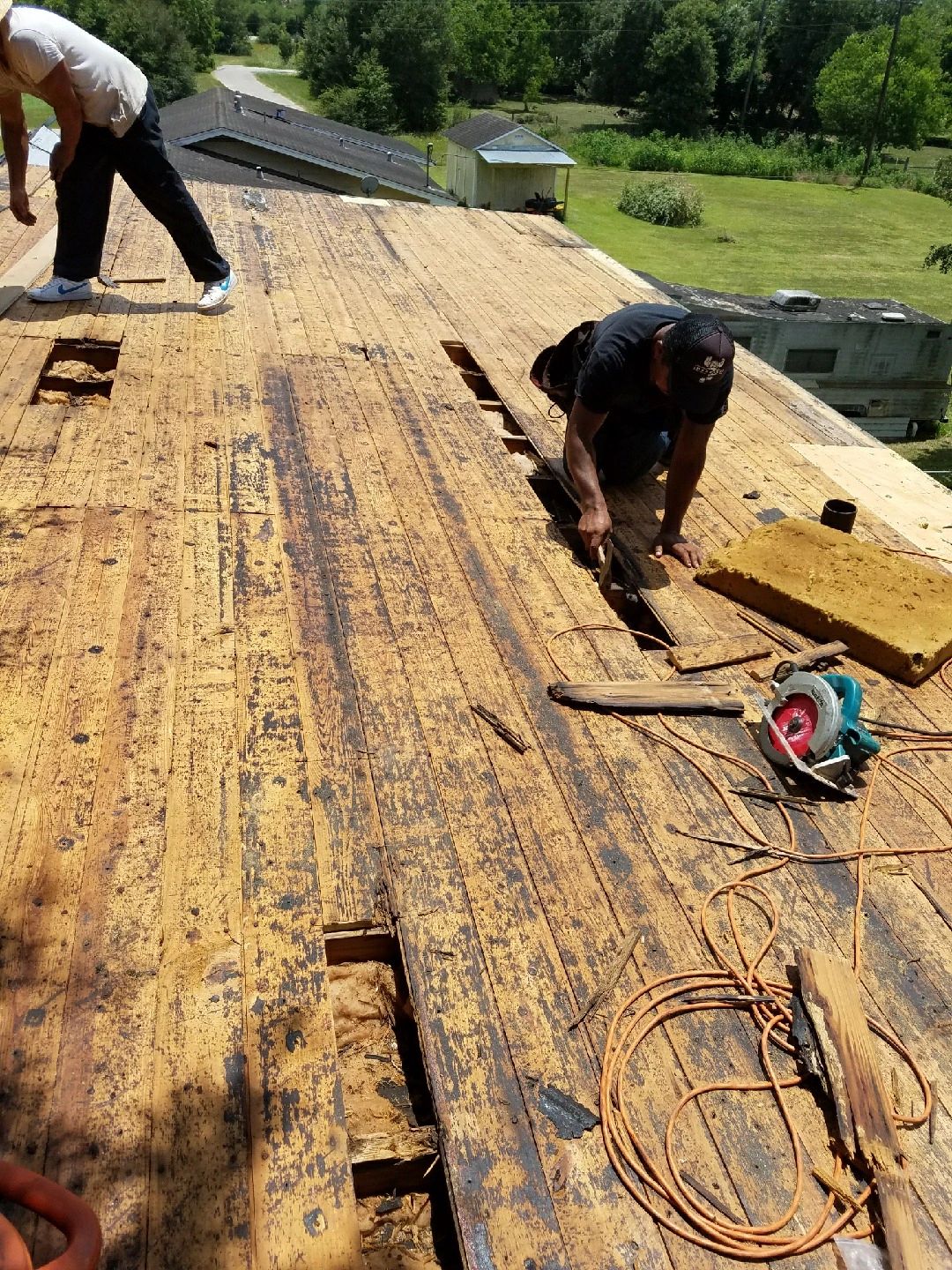 Two workers performing roof repair on large residential structure
